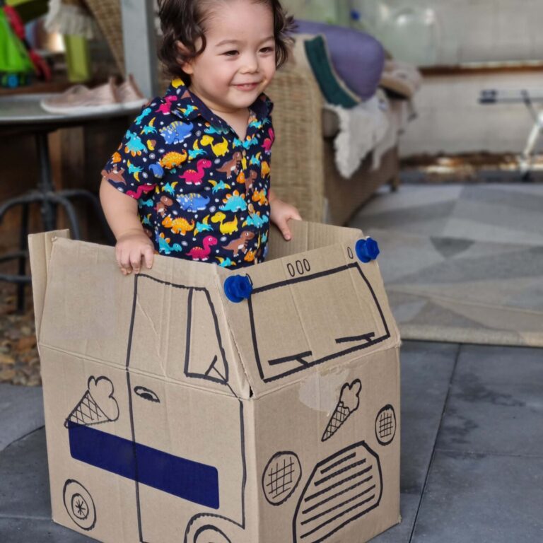 Young child playing in a cardboard box that has been made to look like an ice cream truck made using the SōZō Play system. 